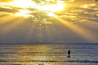 Silhouette woman by sea against sky during sunset