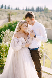 Portrait of bride with groom standing outdoors