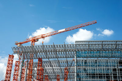 Low angle view of crane at construction site against sky