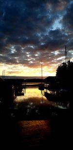 Silhouette bridge over river against sky during sunset