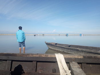 Rear view of man standing on pier against sea