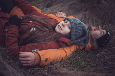 Portrait of woman lying on field with man outdoors