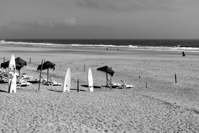 Deck chair on beach against cloudy sky