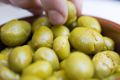 A man takes pickled olive from a saucer with his fingers.