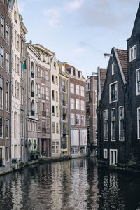 Buildings by river against sky