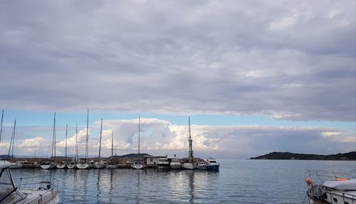 Sailboats moored at harbor against sky