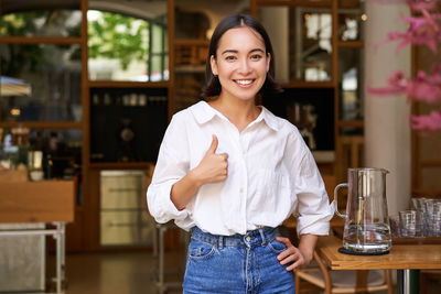 Portrait of young woman standing in cafe