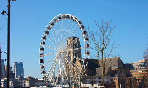 Low angle view of ferris wheel against buildings in city