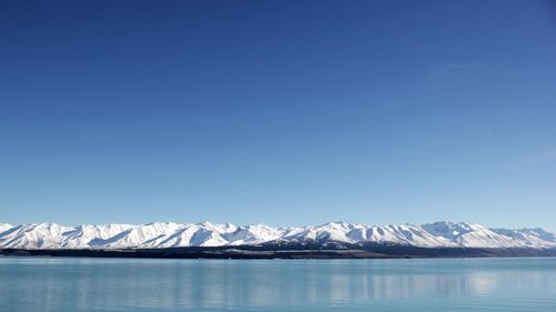 Scenic view of snowcapped mountains against blue sky