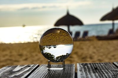 Close-up of glass on table by sea against sky