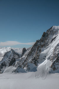 Scenic view of snow covered mountains against blue sky