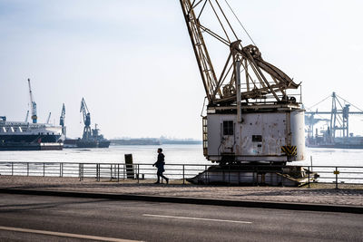 Man fishing at harbor against sky