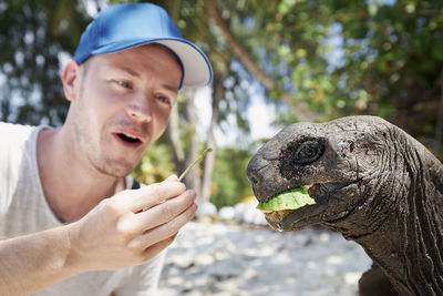 Smiling man feeding tortoise