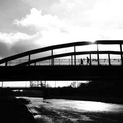 Bridge over river against cloudy sky