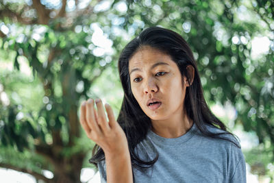 Portrait of young woman against tree