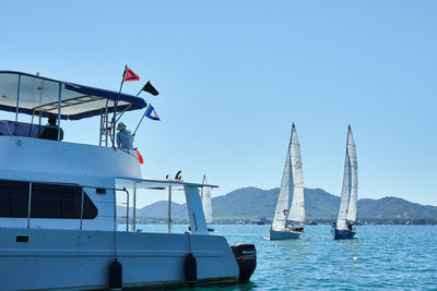 Sailboats sailing in sea against clear sky