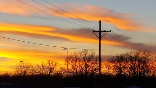 Silhouette electricity pylon against sky during sunset