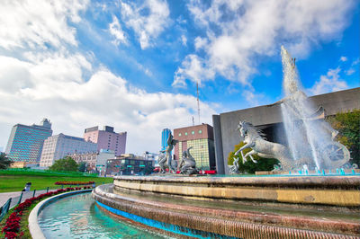 Statue of fountain in city against sky