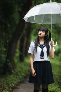 Full length of woman standing in rain during rainy season
