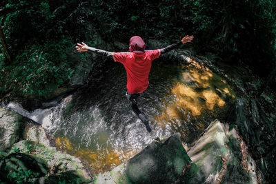 Man standing on rock by river in forest