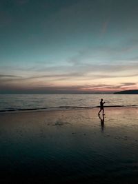 Silhouette people on beach against sky during sunset
