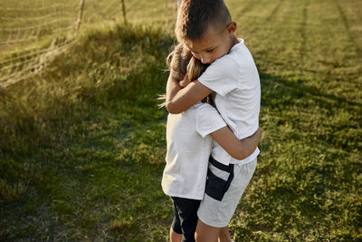 Boy hugging sister at sports field