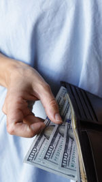 Woman holding few 100 dollar bills from the wallet