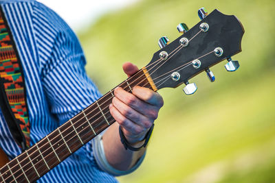 Midsection of man playing guitar