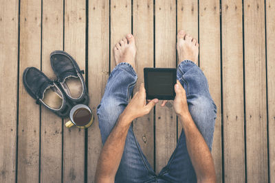 Low section of man using digital tablet while sitting on wood