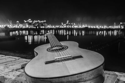 Guitar against river in city at night