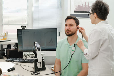 Portrait of doctor talking on phone while standing in hospital