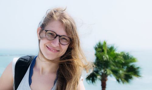 Portrait of smiling young woman standing against sky