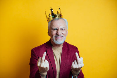 Portrait of smiling man gesturing against yellow background