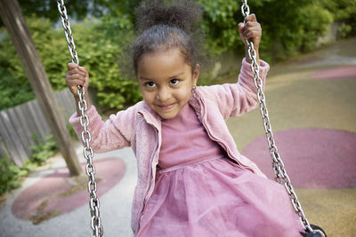 Happy girl having fun on swing in playground