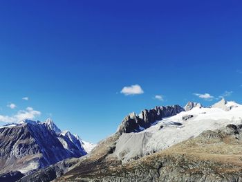 Scenic view of snowcapped mountains against blue sky