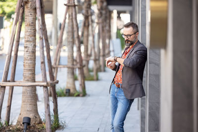 Attractive young businessman in stylish suit looking at watch in business district outdoors person