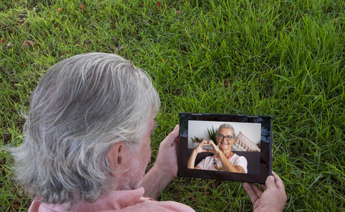 High angle view of senior man video calling while using digital tablet