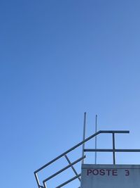 Low angle view of information sign against clear blue sky