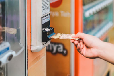 Close-up of hand holding paper currency at atm machine