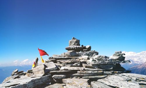 Low angle view of flag on rock against blue sky