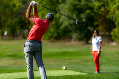 Young couple on a golfing vacation, man teeing off