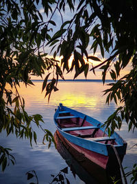 Boats moored in sea at sunset