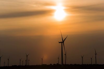 Low angle view of silhouette windmill on field against sky during sunset