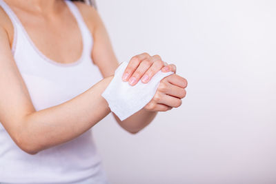 Midsection of woman holding hands against white background