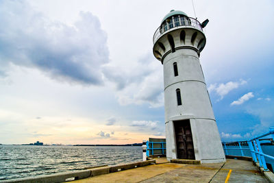 Lighthouse by sea against sky