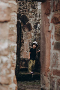 Man standing by tree trunk against building