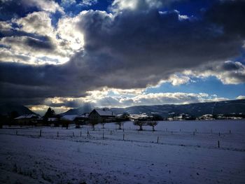 Scenic view of landscape against cloudy sky during sunset