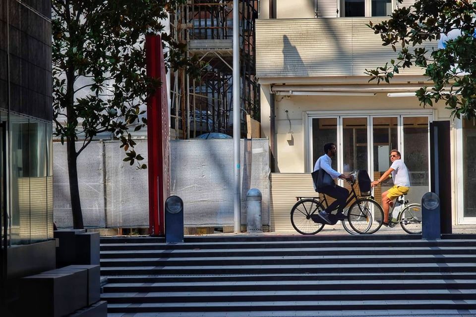 PEOPLE RIDING BICYCLE ON STREET AGAINST BUILDING