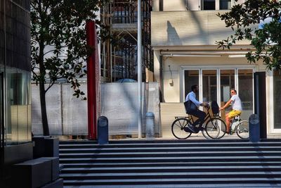 Man riding bicycle on street against building in city