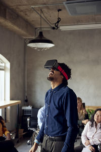 Businessman wearing vr simulator while standing at creative office